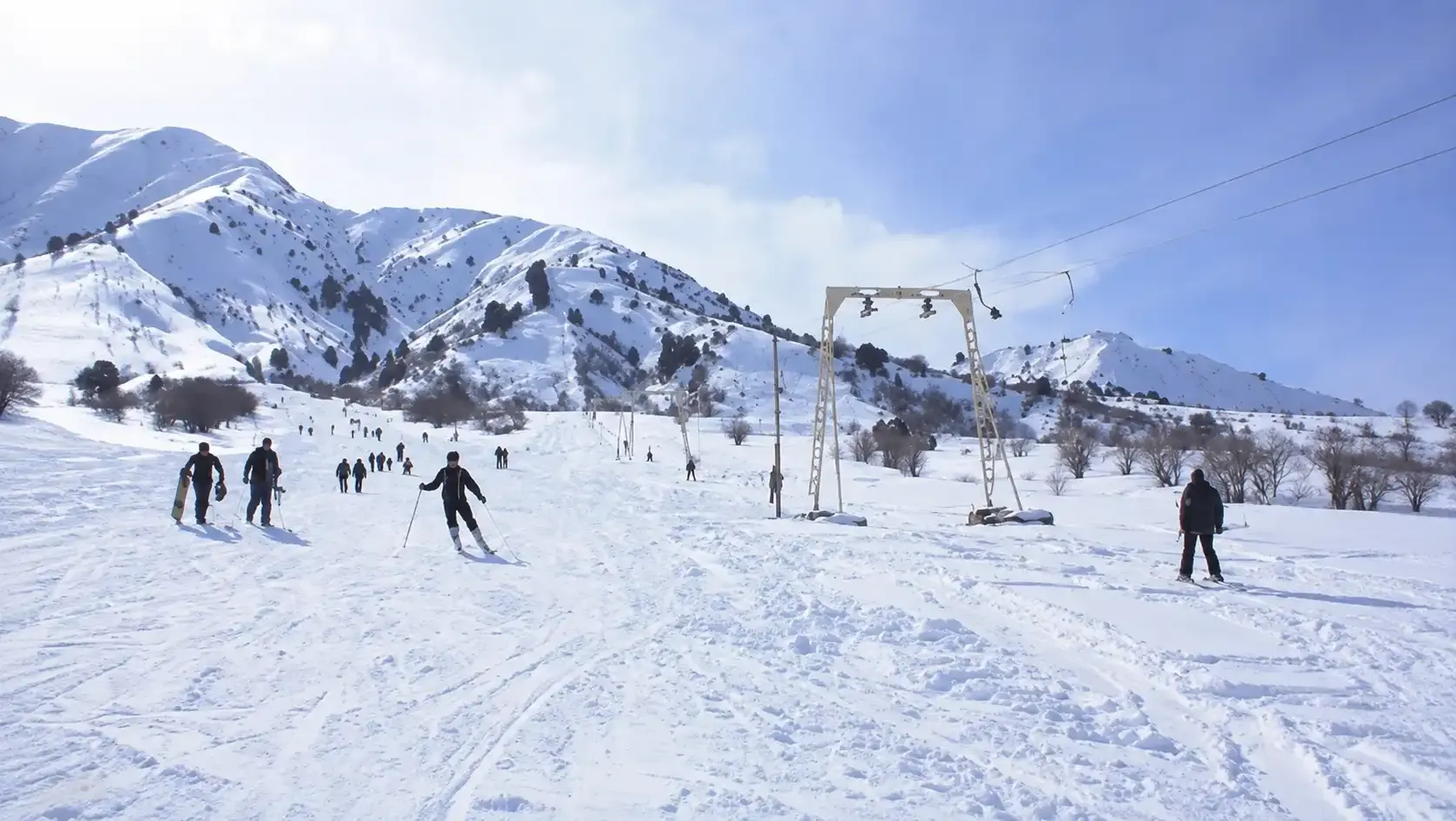 Skiers and snowboarders on the open Chimgan slope beside the old drag lift.